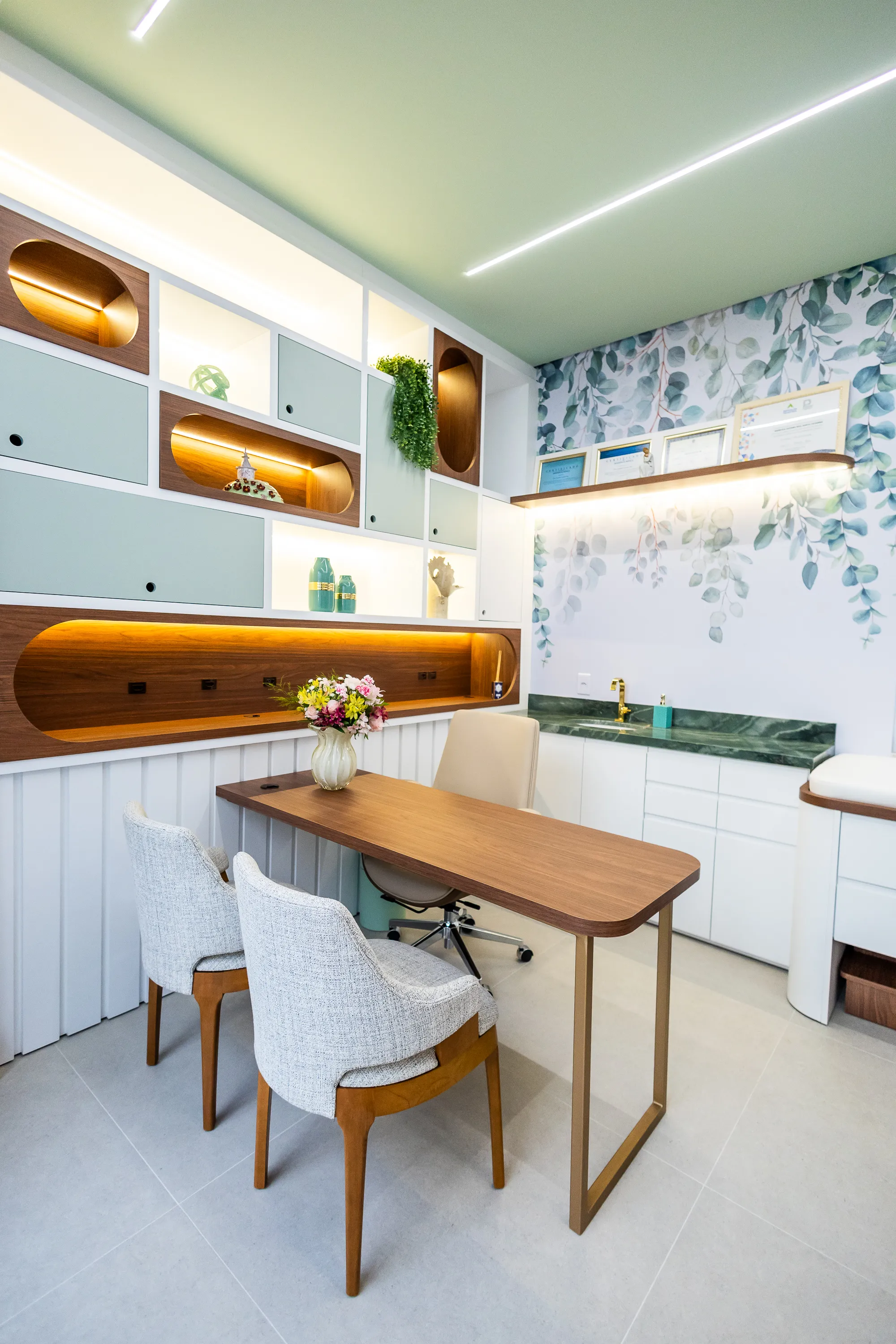 Consultório da Casalume — vista lateral com mesa, cadeiras acolhedoras e papel de parede botânico
